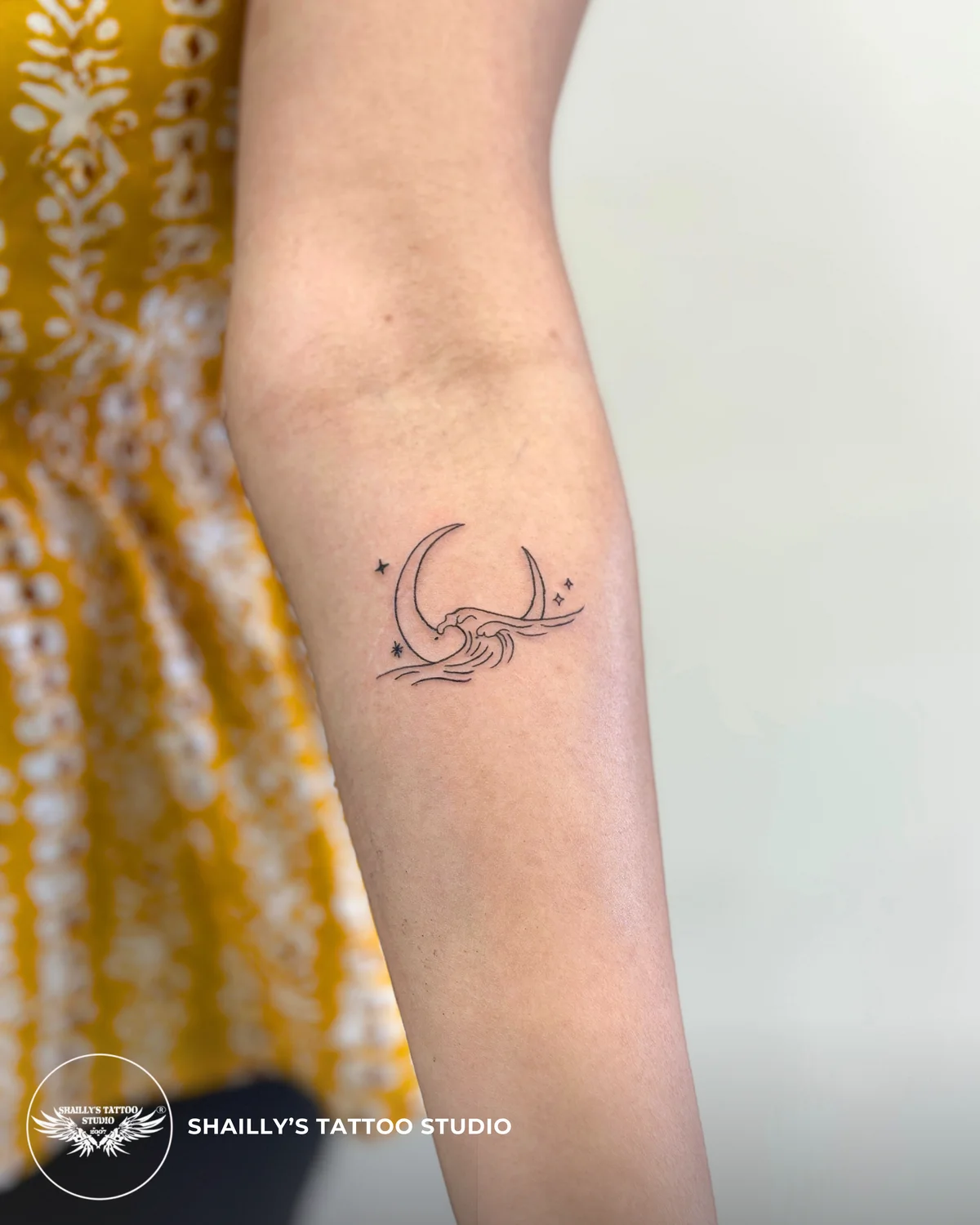 Small abstract fine-line tattoo on an inner forearm